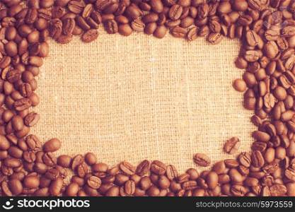 Spilled coffee beans frame over burlap textile. coffee beans frame