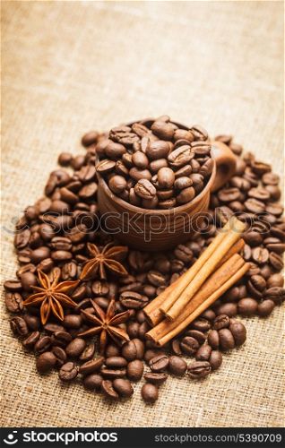 Spilled coffee beans in clay handmade cup with cinnamon and anise