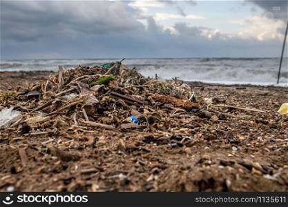 Spilled garbage on the beach of the big city. Empty used dirty plastic bottles. Dirty sea sandy shore. Environmental pollution. Ecological problem. Bokeh moving waves in the background. pollution on beach