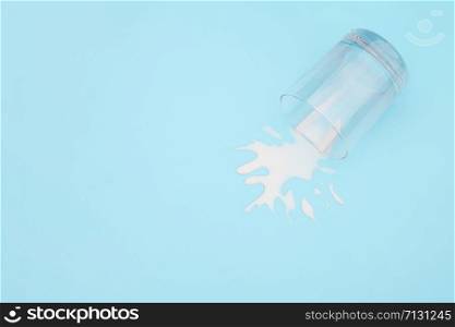 Spilled milk. Overturned glass with milk on blue background. Dairy abandonment concept Copy space Top view.. Spilled milk. Overturned glass with milk on blue background. Dairy abandonment concept Copy space Top view