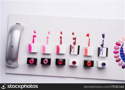 spilled nail polishes with bottle and LED lamp on white background. flat lay