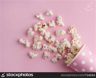 Spilled popcorn on a pink background, cinema, movies and entertainment concept