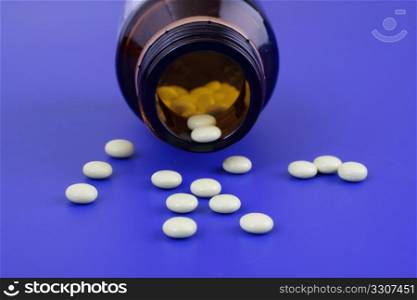 Spilled tablets and medicine bottle. Tablets on a blue background