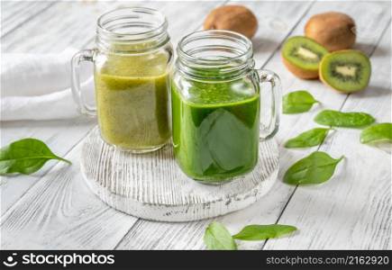 Spinach and kiwi smoothie in mason jars on the wooden board