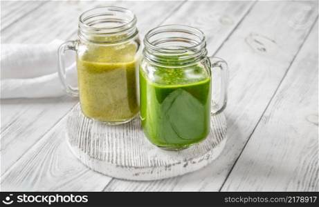 Spinach and kiwi smoothie in mason jars on the wooden board