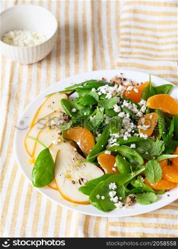 Spinach and quinoa salad with pears, oranges and ricotta. Healthy Meal prep. Plant-based dishes. Green living. Vegan recipe. Food styling. Vegetarian cuisine. Healthy eating. Weight loss food concept.