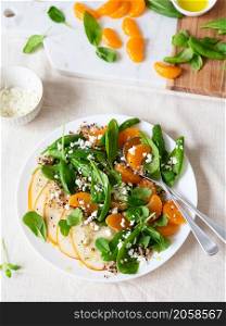 Spinach and quinoa salad with pears, oranges and ricotta. Healthy Meal prep. Plant-based dishes. Green living. Vegan recipe. Food styling. Vegetarian cuisine. Healthy eating. Weight loss food concept.