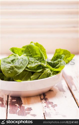 Spinach leaves in a bowl on the table. The spinach leaves