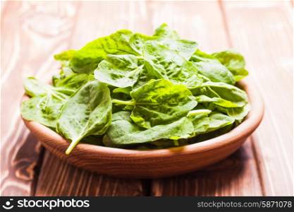 Spinach leaves in a wooden bowl on the table