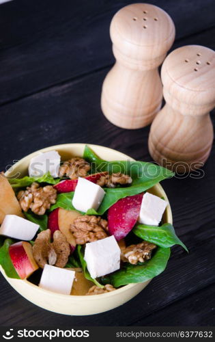 Spinach salad with nuts and apples served on table