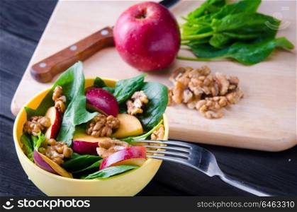 Spinach salad with nuts and apples served on table