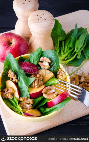 Spinach salad with nuts and apples served on table