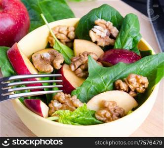 Spinach salad with nuts and apples served on table. The spinach salad with nuts and apples served on table