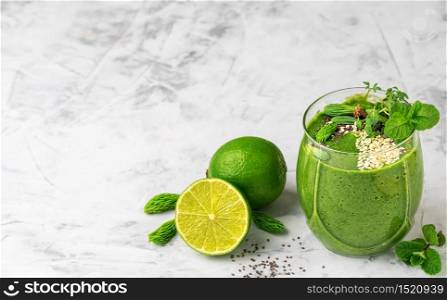 Spinach smoothie with banana, lime, chia and sesame seeds and microgreens in a glass beaker. Close-up with copy space.