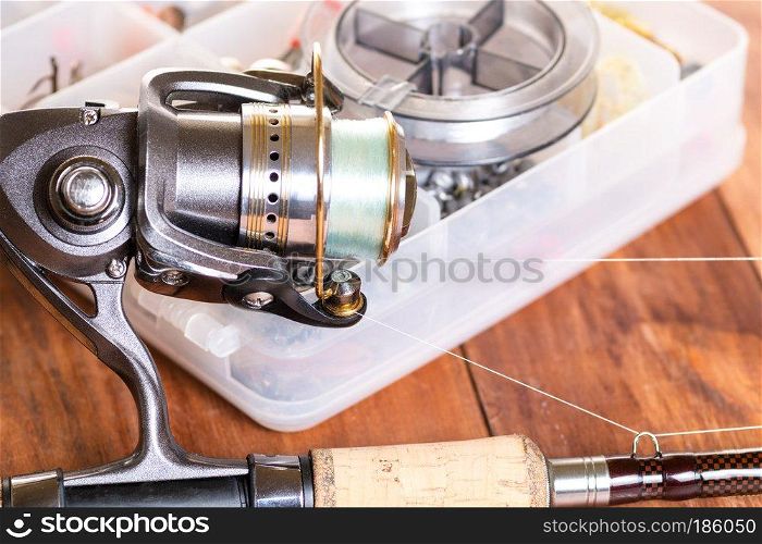 Spinning and boxes with fishing tackle on wooden boards. Fishing tackle on wooden blue background