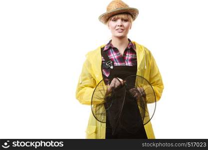 Spinning, angling, cheerful fisherwoman concept. Happy woman in yellow raincoat holding empty fishing keepnet, having fun.. Happy woman holding empty fishing keepnet