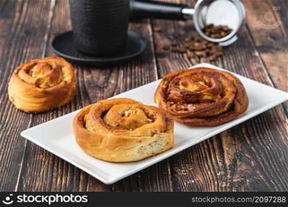Spiral apple cake or muffin with cup of fresh coffee on wooden background