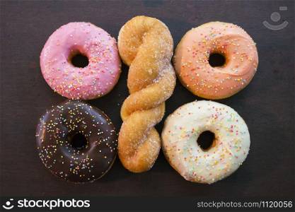 spiral donut with four glazed donut lying on wooden background