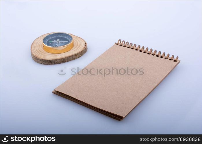 Spiral notebook and a compasson a white background
