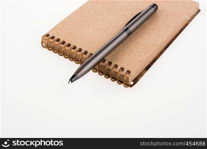 Spiral notebook and pollpoint pen on a white background