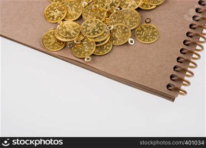 Spiral notebook and the gold coins on white background