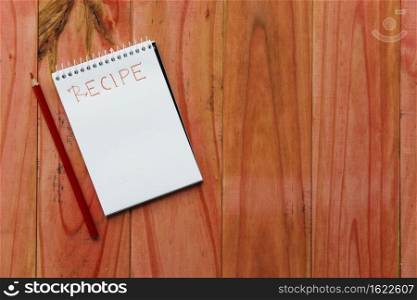 spiral notepad near recipe word near pencil wooden background