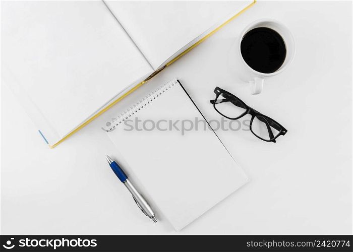 spiral notepad spectacles cup pen book white background