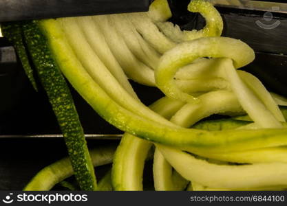 Spiralizer with spiralised zucchini or courgette, macro.