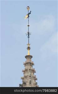 Spire with gold-trimmed weathercock, and blue sky in background