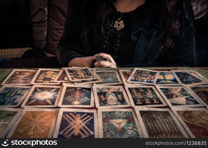 Spiritual wicca witch reading occult mystic old tarot cards laying on table for a magical pagan ritual psychic destiny reading - Concept of supernatural, witchcraft, destiny and mystical fortune-telling.