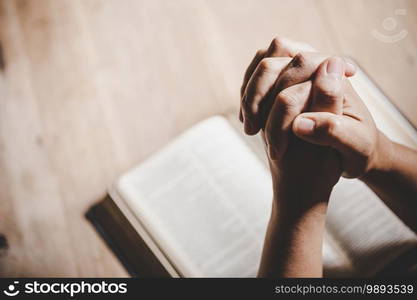 Spirituality and religion, Hands folded in prayer on a Holy Bible in church concept for faith.