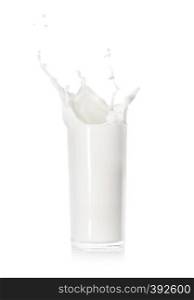 Splash of fresh milk in glass cup isolated on white background. Splash of fresh milk in a glass cup
