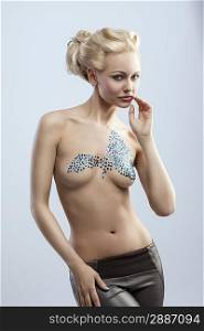 splendid blonde woman with creative hair-style shows her naked body with bright decorations on breast