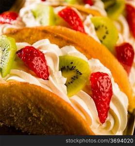 Sponge cake filled with strawberry and kiwi on whipped cream