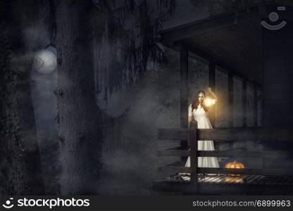 Spooky girl, in a white dress, holding a lit lantern, a pumpkin near her, on the balcony of a wooden house, in a dark foggy forest, under the moonlight.