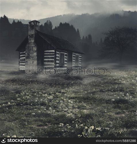 Spooky landscape with alone haunted house against dark mountain