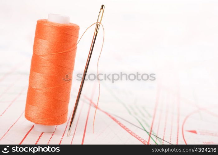 Spool of thread and needle. Sew accessories on blurred background.