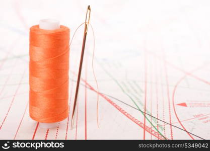 Spool of thread and needle. Sew accessories on blurred background.