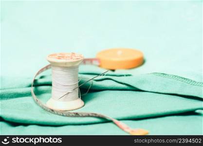 Spool of thread and sewing needle,measuring tape on the cotton cloth material