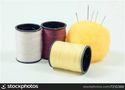 Spools of colorful thread and needle. Accessories for sewing and needlework. Spools of thread and needle. Accessories for needlework