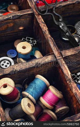 Spools of thread and buttons. Sewing kit with threads and buttons in the cells wooden box