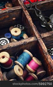 Spools of thread and buttons. Sewing kit with threads and buttons in the cells wooden box