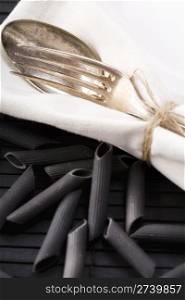 spoon and fork on white napkin and italian pasta