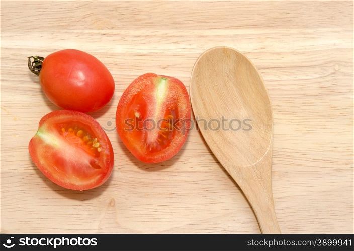 Spoon and tomato on the wood.