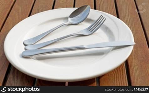 spoon fork and knife on empty white plate