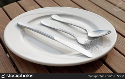 spoon fork and knife on empty white plate