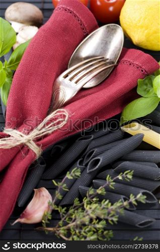Spoon, fork, napkin and pasta ingredients (Penne, basil, mushrooms, tomato, lemon)