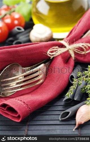 Spoon, fork, napkin and pasta ingredients (Penne, olive oil, basil, mushrooms, tomato, lemon)