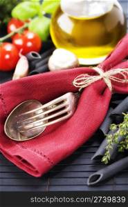 Spoon, fork, napkin and pasta ingredients (Penne, olive oil, basil, mushrooms, tomato, lemon)