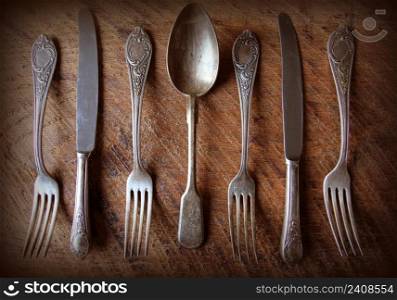 Spoon, forks, knives, ladles on a wooden table, selective focus and toned image . Top view .. Spoon, forks, knives, ladles on a wooden table, selective focus and toned image. Top view